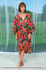 Monika g posing in an elegant vibrant floral dress that accentuates her petite body