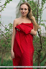 Tayra a playfully posing with a bright red fabric wrapped around her delicate, naked body
